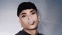 a man with makeup on his face is smoking a cigarette and making a funny face .