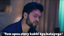 a man with a beard is sitting in a room with a caption that says tum apna story kabhi kyu batayega