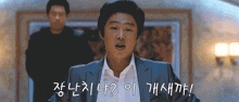 a man in a suit and white shirt is standing in front of a wall with chinese writing on it