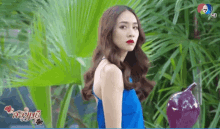 a woman in a blue dress is standing in front of a purple vase