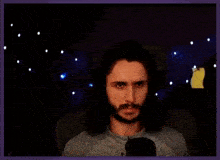 a man with long hair and a beard is sitting in front of a microphone making a face .