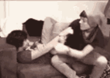 a couple of people are sitting on a couch and fighting .