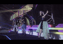 a group of women are singing on a stage with a large screen behind them