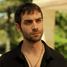 a man with a beard wearing a black shirt and necklace