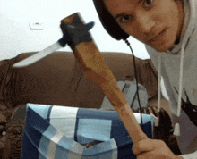 a man wearing headphones holds a wooden stick with a knife on it