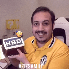 a man in a yellow shirt is holding a cake with the word hbd on it