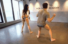 a man and a woman are dancing in a dance studio with a sign that says noa dance academy .