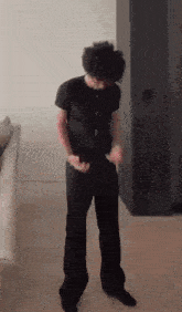 a man in a black shirt and black pants is dancing in a room