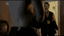 a man without a shirt is standing in front of a door with the letter e on the bottom
