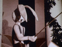 a black and white photo of a stuffed bunny rabbit holding a stick