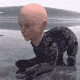a bald baby is crawling on a gray surface .