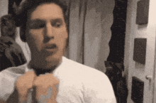 a man in a white shirt is adjusting his tie in front of a mirror