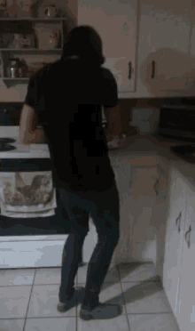 a man in a black shirt stands in front of a stove