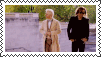 a couple of people standing next to each other on a sidewalk in a postage stamp .