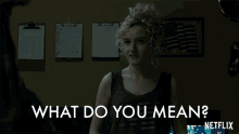 a woman with curly hair is standing in front of a wall that says what do you mean on it
