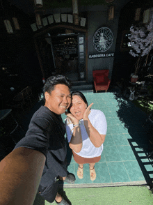 a man and a woman pose for a picture in front of kabesara cafe