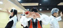 a group of people are making a heart shape with their hands in a room