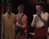 a group of men are standing next to each other on a stage in a dark room .