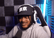 a man wearing headphones and a black hat with chinese writing on it
