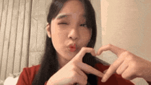 a woman is making a heart shape with her fingers .