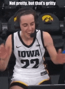 a woman in a iowa basketball jersey is wearing headphones and smiling