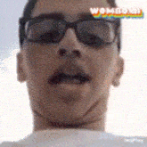 a close up of a man wearing glasses and a white shirt with the word wow on the bottom