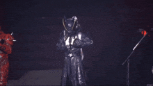 a person in a black costume is standing on a stage with a microphone