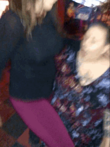 a woman in a black shirt is standing next to a woman in purple pants