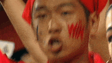 a man with red paint on his face has the word win on his face .