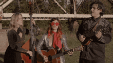a man and two women playing guitars and a man playing a bass