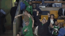 a man in a green sweatshirt with the number 3 on it stands in a crowd