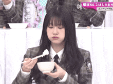 a girl in a plaid jacket is holding a bowl of food