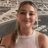 a woman in a pink tank top is smiling in front of an eiffel tower .