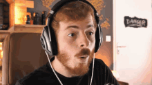 a man wearing headphones with a danger sign in the background