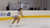 a woman is ice skating in front of a sign that says " iqlab "