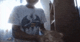 a person wearing a batman t-shirt is holding a cat