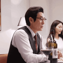 a man sits at a table with a bottle of wine and a glass of wine