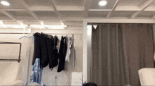 a room with a lot of clothes hanging on racks and curtains