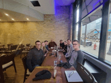 a group of people are sitting at a long table in front of a window that says ' o'dio ' on it