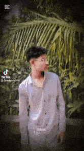 a young man in a white shirt is standing in front of a palm tree