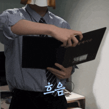 a man in a striped shirt and tie is holding a black book with chinese writing on it