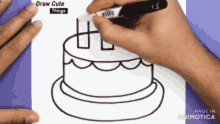 a person is drawing a birthday cake with a marker on a piece of paper
