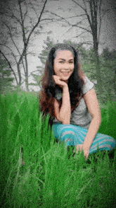 a woman is sitting in the grass and smiling