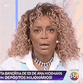a woman with curly hair is wearing a necklace and earrings .