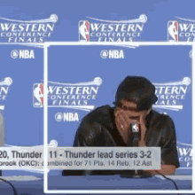 a man is covering his face while talking into a microphone during a western conference finals press conference