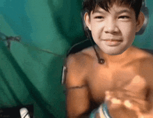 a young boy without a shirt is wearing a headset and smiling