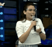 a woman is holding a microphone with a straw in her mouth while wearing a face mask .
