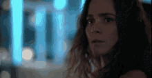 a close up of a woman 's face with a blurry background of blue lights