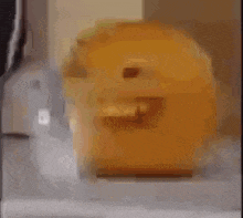 a yellow object with a face on it is sitting on a table next to a blender .
