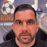 a man with a beard stands in front of a sign that says " ring de jugo "